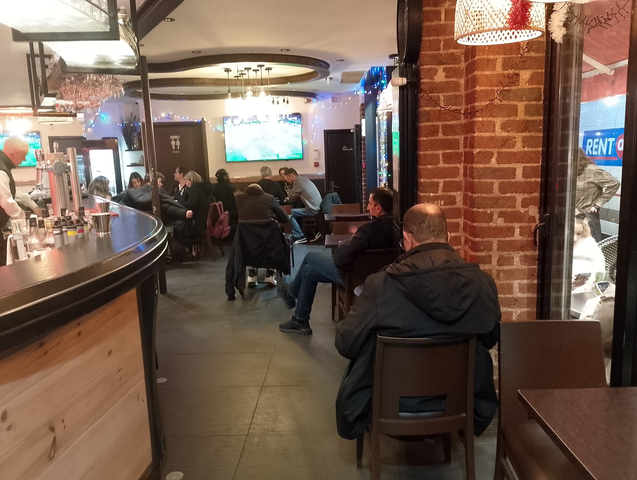 Ambiance conviviale du bar avec clients regardant le match