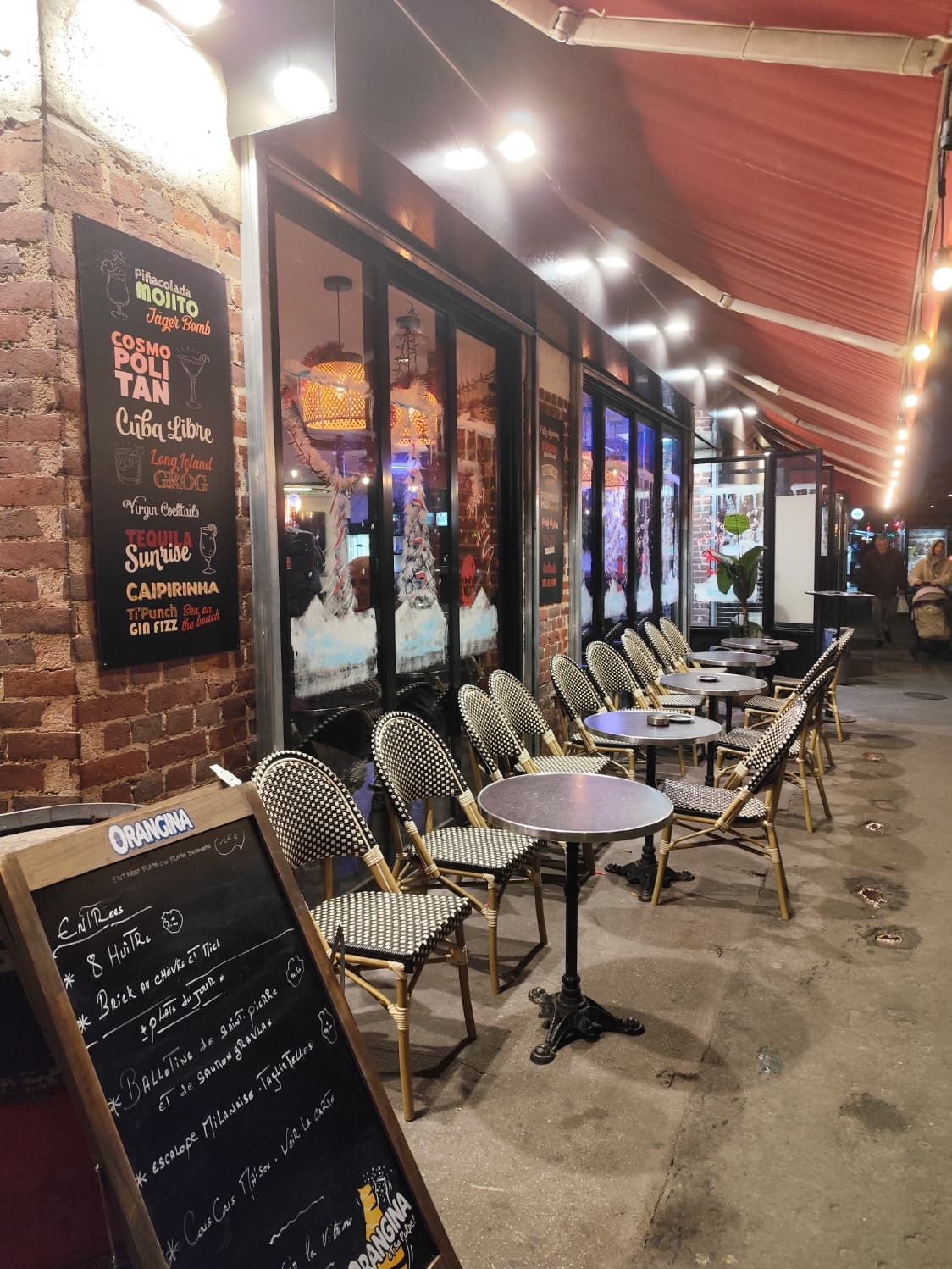 Terrasse de nuit avec chaises parisiennes et ardoise cocktails